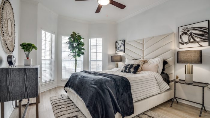 a bedroom with a ceiling fan and white bed at The NEO Midtown